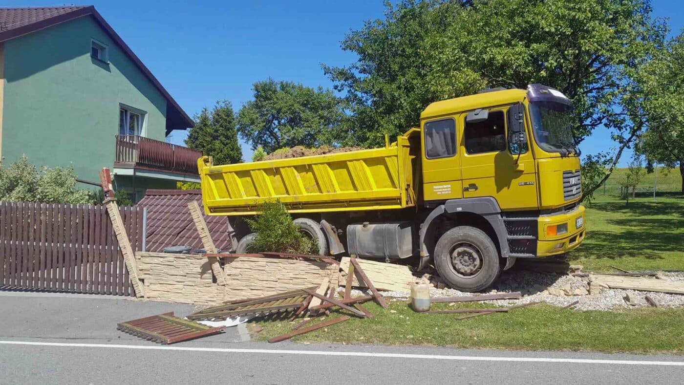 Řidič náklaďáku zkolaboval a vůz pak zbořil plot. Foto: ZZS