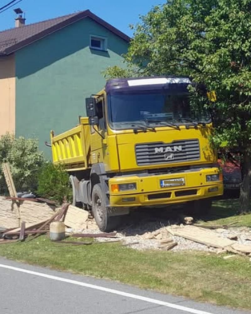 Řidič náklaďáku zkolaboval a vůz pak zbořil plot. Foto: ZZS